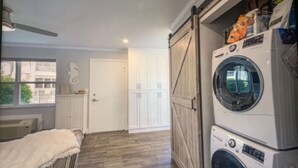 Une buanderie équipée d’un lave-linge et d’un sèche-linge, avec un plancher en bois et une porte blanche.