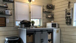 A kitchen with wooden walls, a built-in microwave, a kettle, and a trash can. - Romantic Cabin: Hot Tub, Pet friendly, 2m Whitewater, Concierge, Private driver (Canyon Lake)