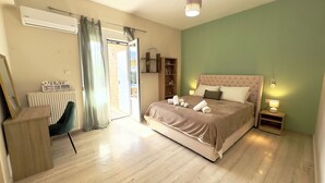 Ein Schlafzimmer mit Bett, Nachttischen, Schreibtisch, Stuhl, Heizkörper und einem Fenster mit Vorhängen.