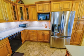 Una cocina con armarios de madera, un refrigerador de acero inoxidable, un microondas y un lavavajillas.