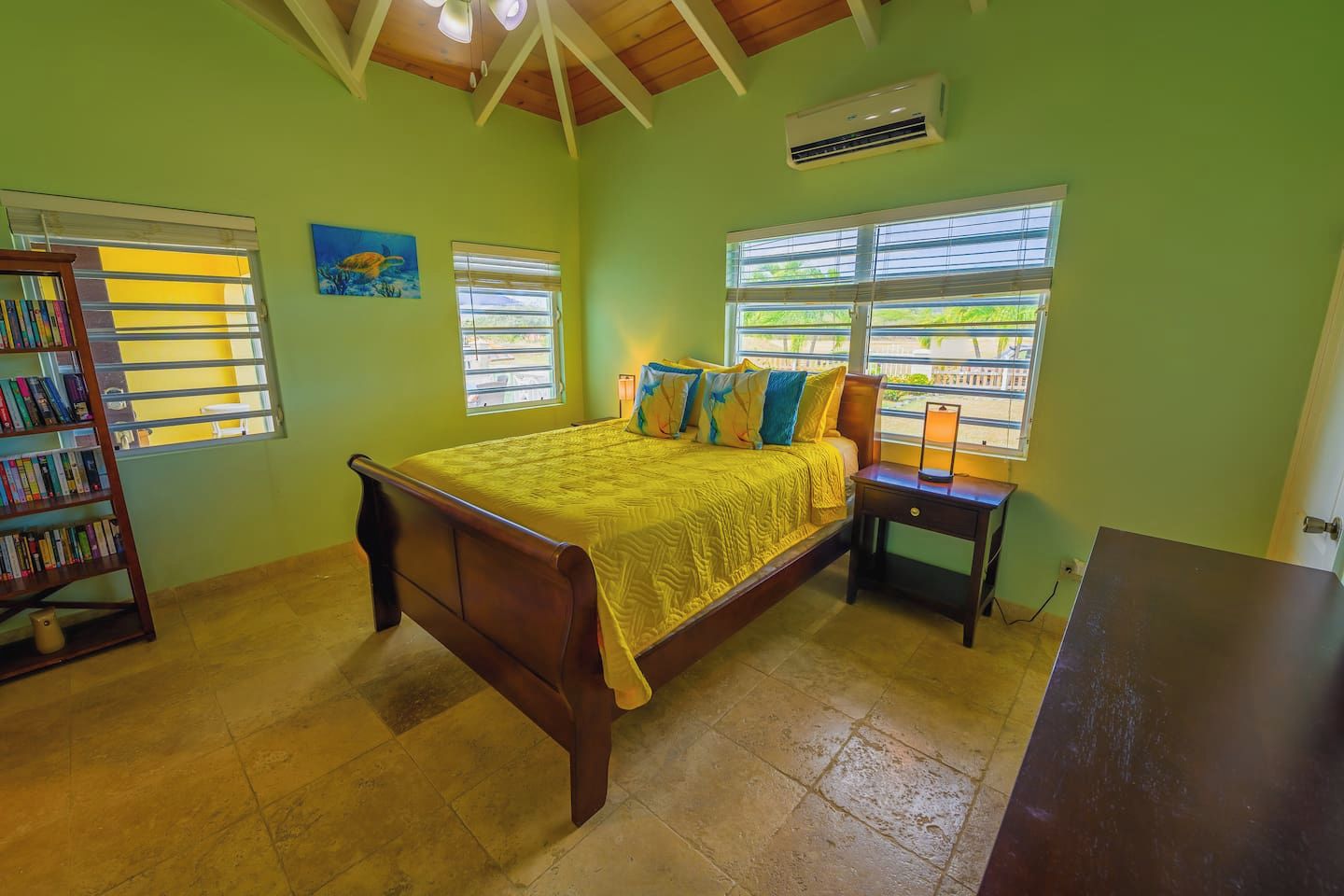 A bedroom with a bed, a nightstand, a bookshelf, and a window with blinds.