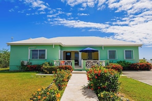 A two-story house with a front porch, a covered entryway, and a well-maintained lawn with flower beds. - Perfect 4BDRM for families or groups! (Frederiksted)