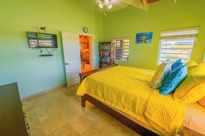 Ett sovrum med en säng, en tv, en bokhylla och ett fönster med persienner.
