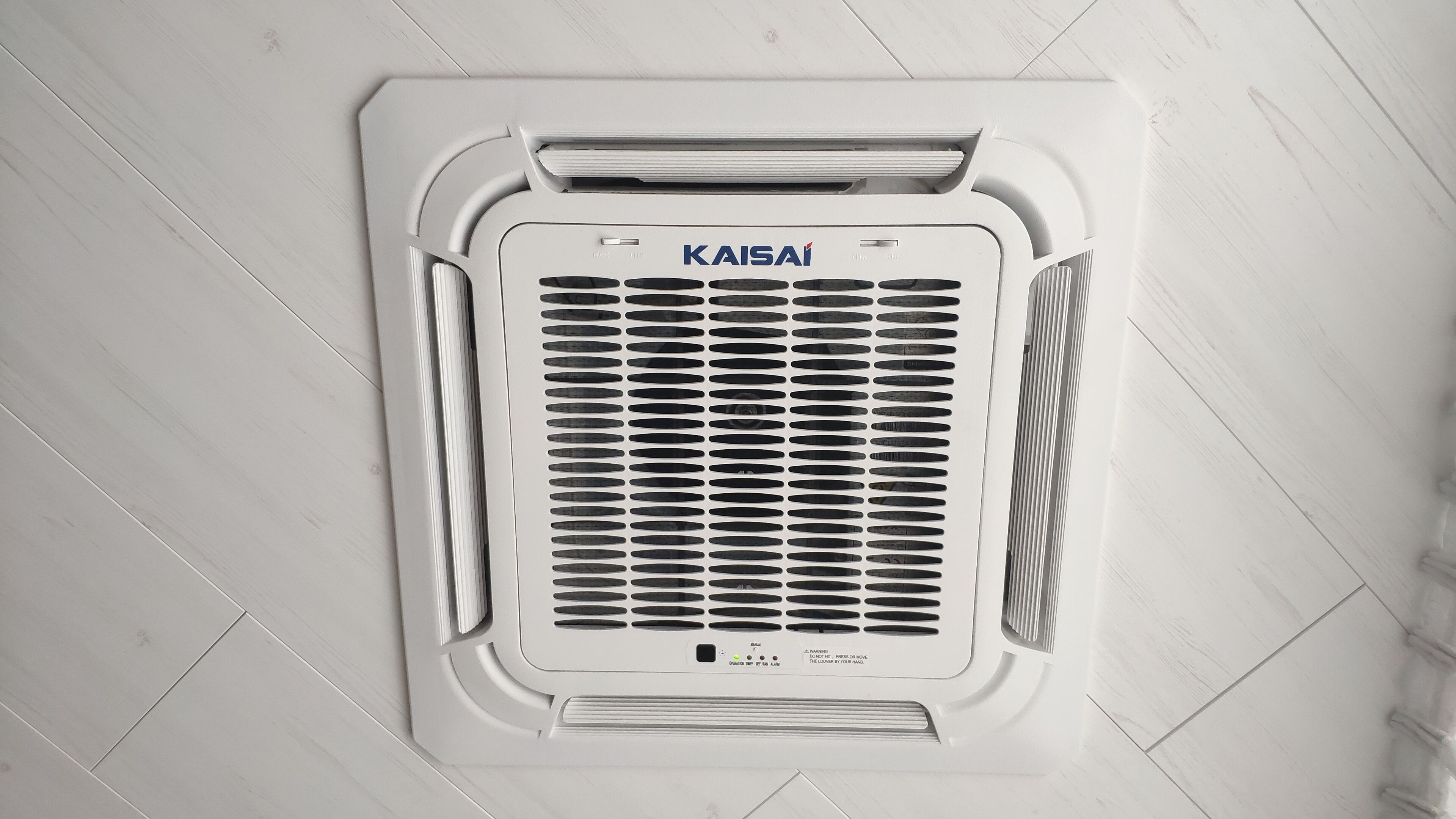 Eine weiße Klimaanlage mit dem Markennamen 'KAISAI' auf einem Fliesenboden.