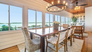 A dining area with a large wooden table, wicker chairs, and a view of the water. - Amazing Lake House - beautiful clear lake - 2 hours from Chicago! (Sturgis)
