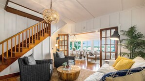 A spacious living area with a wooden staircase, a round coffee table, and a sofa with yellow pillows. - Amazing Lake House - beautiful clear lake - 2 hours from Chicago! (Sturgis)
