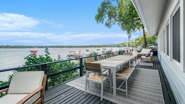 A wooden deck with outdoor furniture overlooking a lake, boats, and a clear sky. - Amazing Lake House - beautiful clear lake - 2 hours from Chicago! (Sturgis)