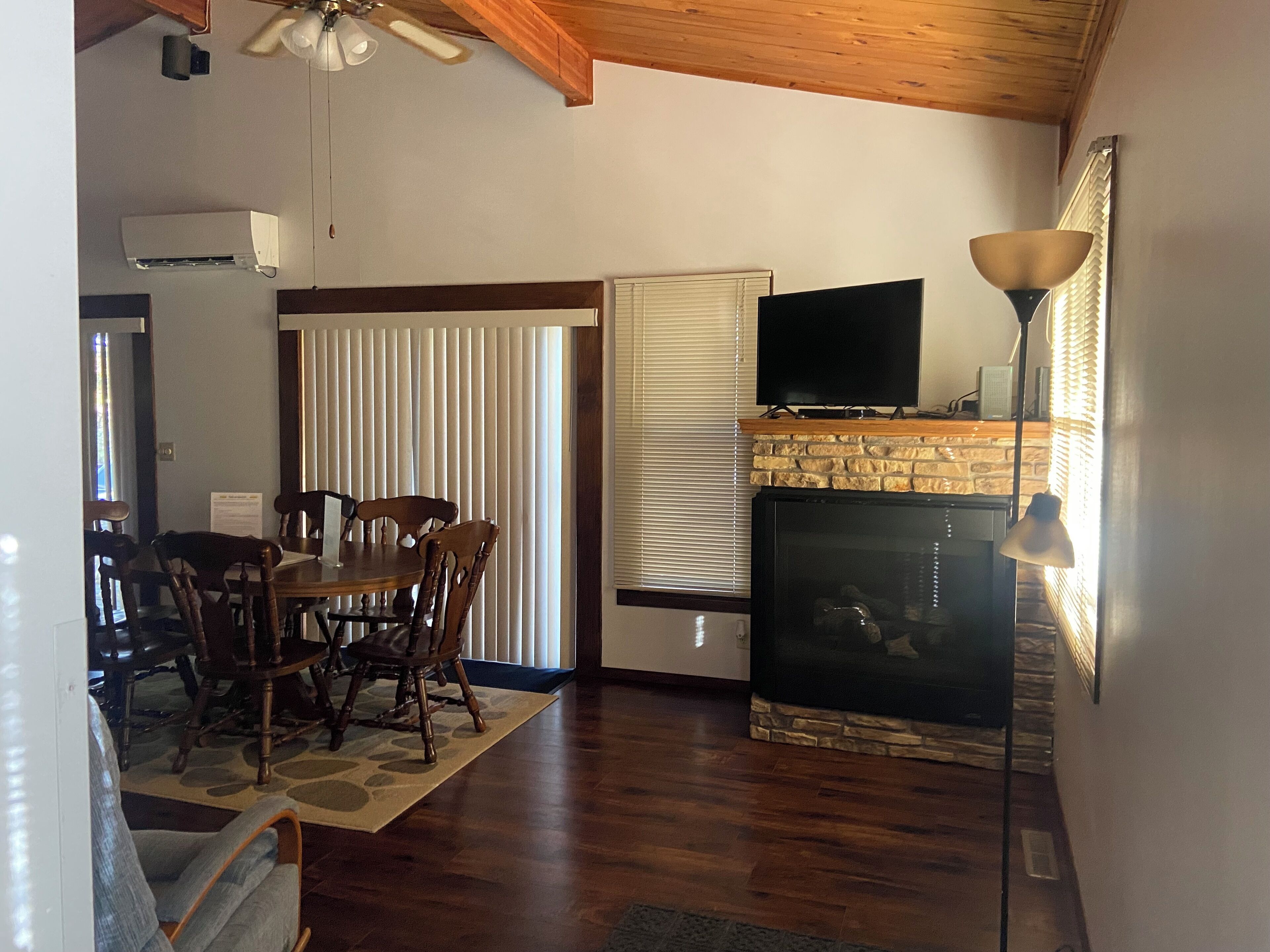 A living room with a fireplace, a television, and a dining area with wooden furniture.