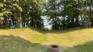 A grassy area with a circular stone structure and a path leading to a body of water. - Poskin Lake Getaway Cabin Lakefront access and beautiful sunrise (Almena)