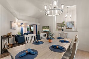 A dining area with a long table, chairs, and a chandelier.