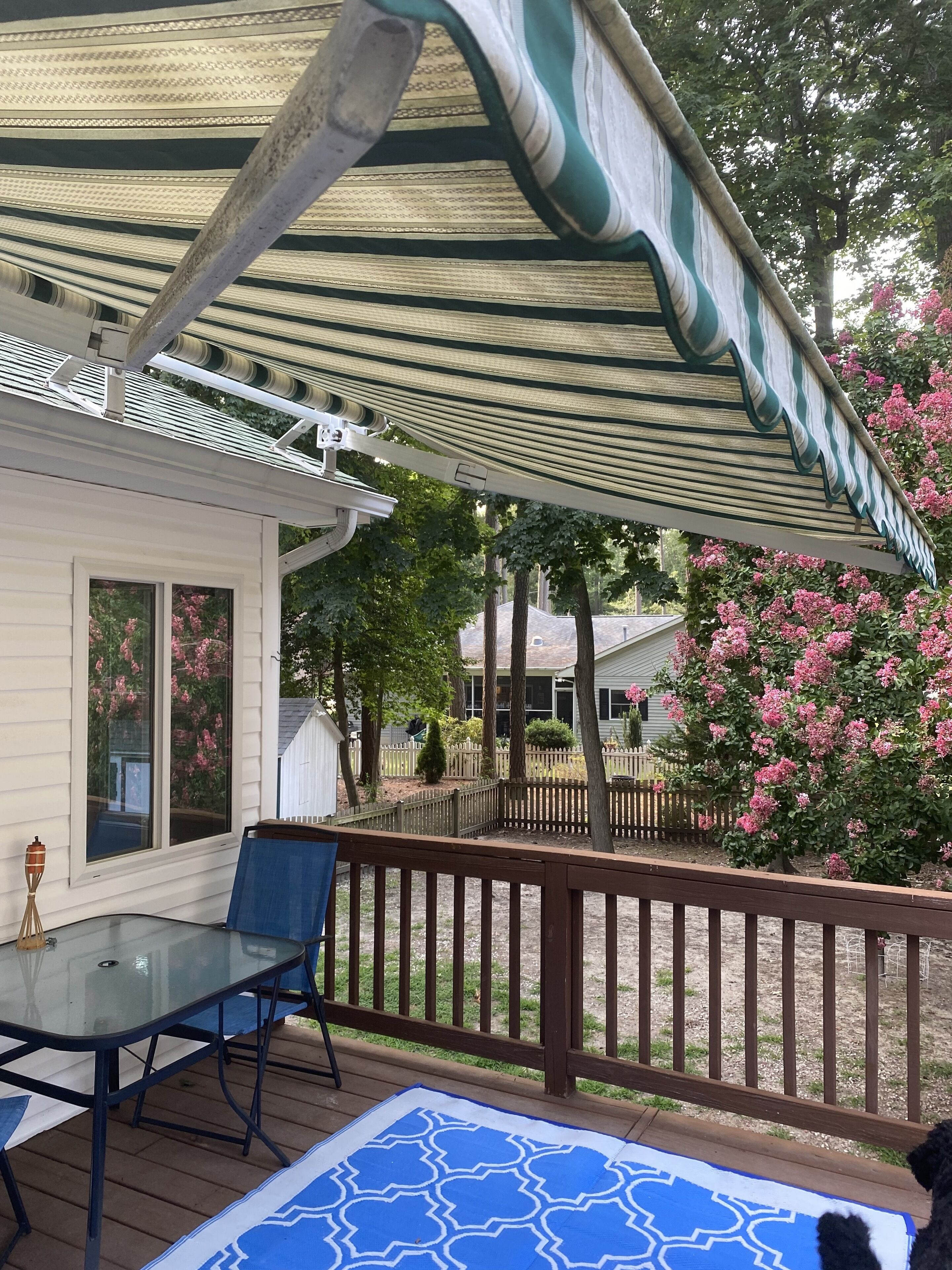 A covered patio with a table and chairs, a wooden deck, and a view of the neighborhood.