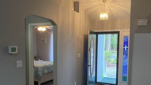 Un corridoio con un letto, un termostato e una porta che dà sull'esterno.