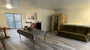 Un grand espace de vie comprenant une table à manger, un canapé et une cuisine en arrière-plan.