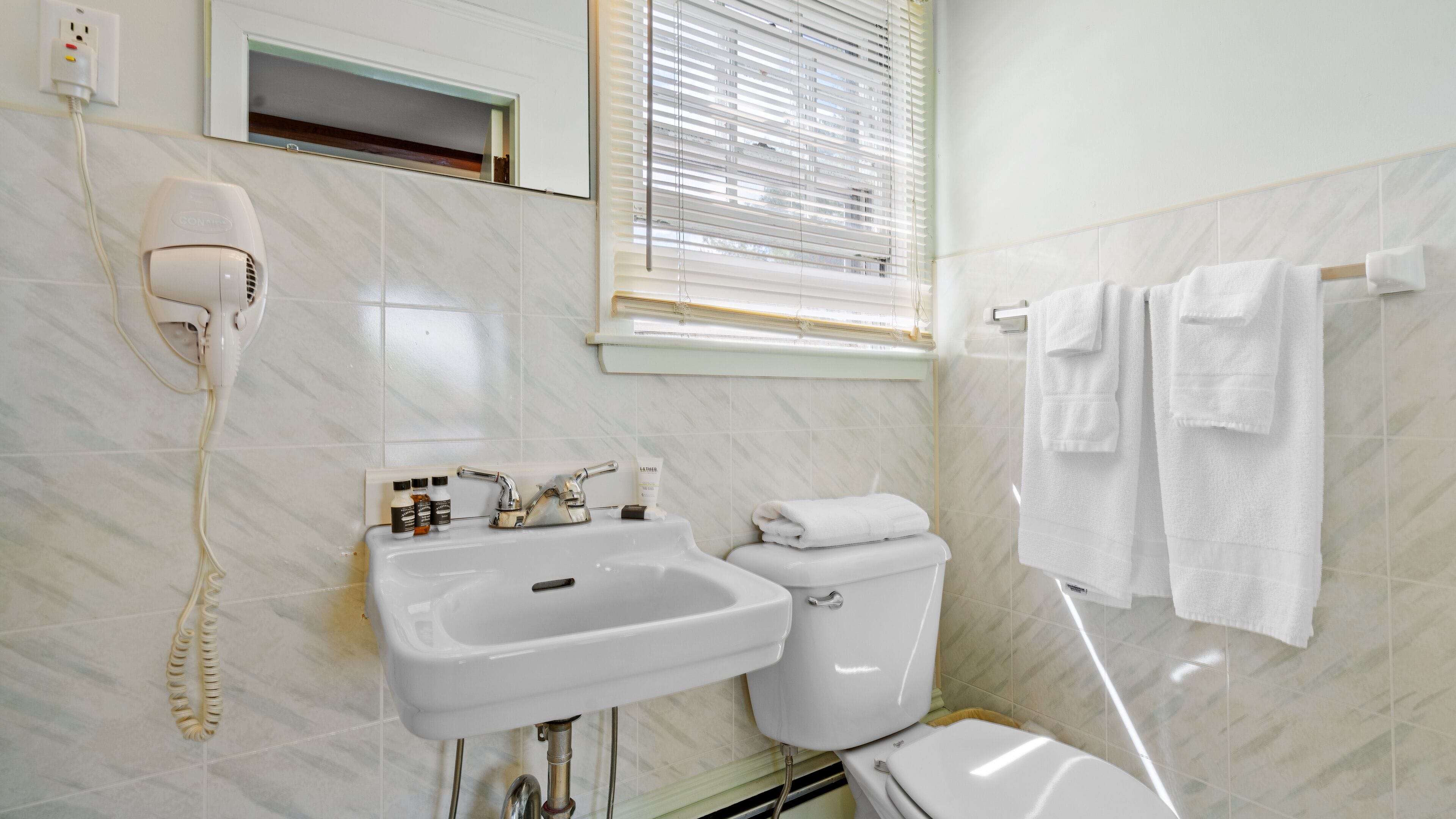 Un baño con lavamanos, inodoro y perchero para toallas.