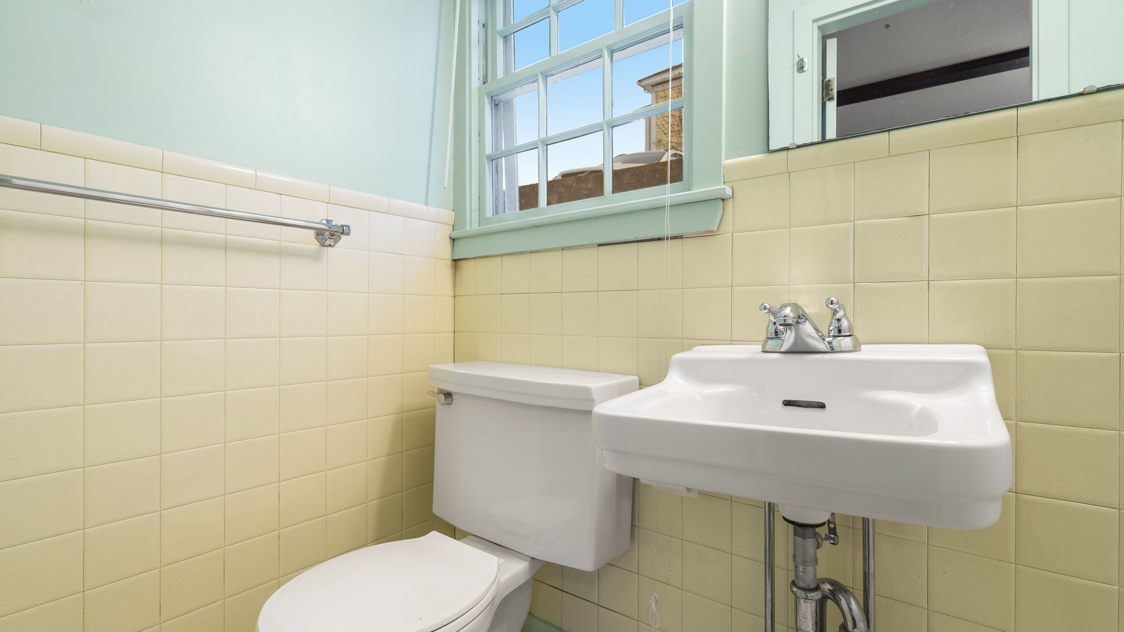 Een badkamer met toilet, wastafel en raam.