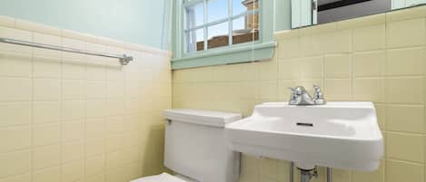 A bathroom with a toilet, sink, and window.