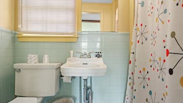 Een badkamer met toilet, wastafel en douchegordijn met een geometrisch patroon.