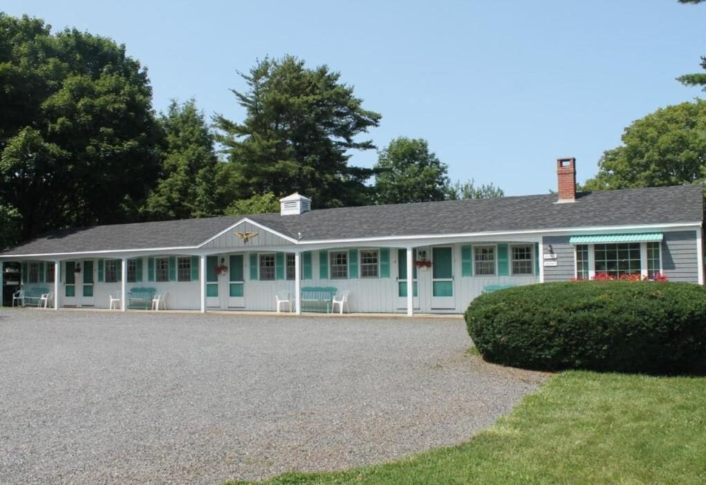 Un motel à deux étages avec une allée en gravier et une petite pelouse.