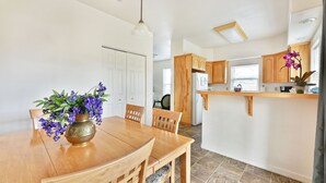Una cocina moderna con armarios de madera, una isla central y un área de comedor con mesa y sillas de madera.