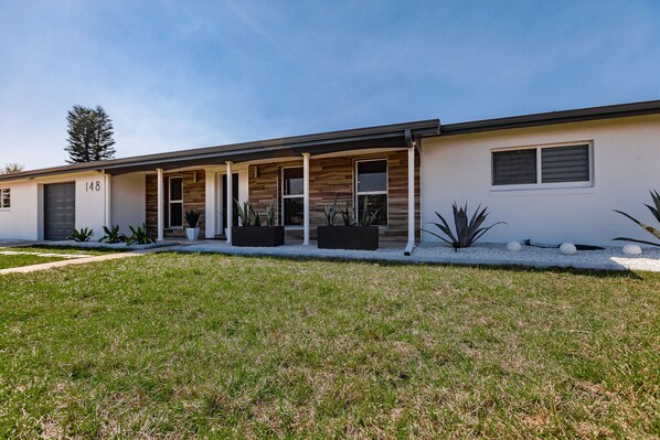 A modern two-story house with a covered porch, number 148, and a well-maintained lawn.