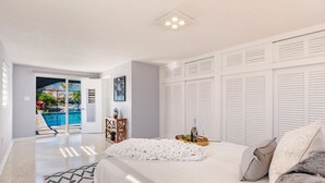 Une chambre avec un grand lit, une vue sur une piscine et un plafond blanc.