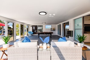 A spacious indoor area with a pool table, wicker furniture, and potted plants. - NEW MODERN 4/3 WATERFRONT HEATED POOL GULF ACCESS FLORIDA HOME (Port Charlotte)