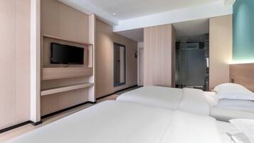 A modern hotel room with a flat-screen TV, a mirror, and a shower area.