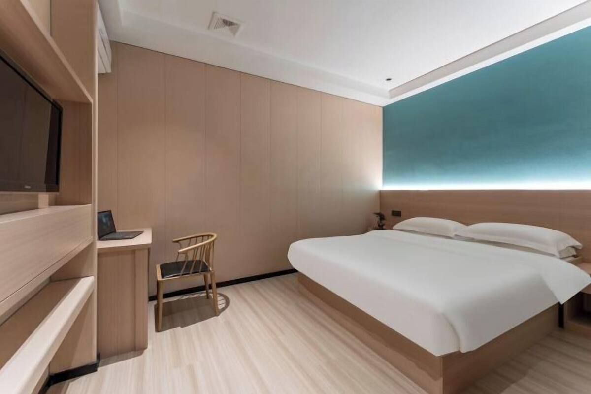 A modern hotel room with a bed, a desk, and a chair.
