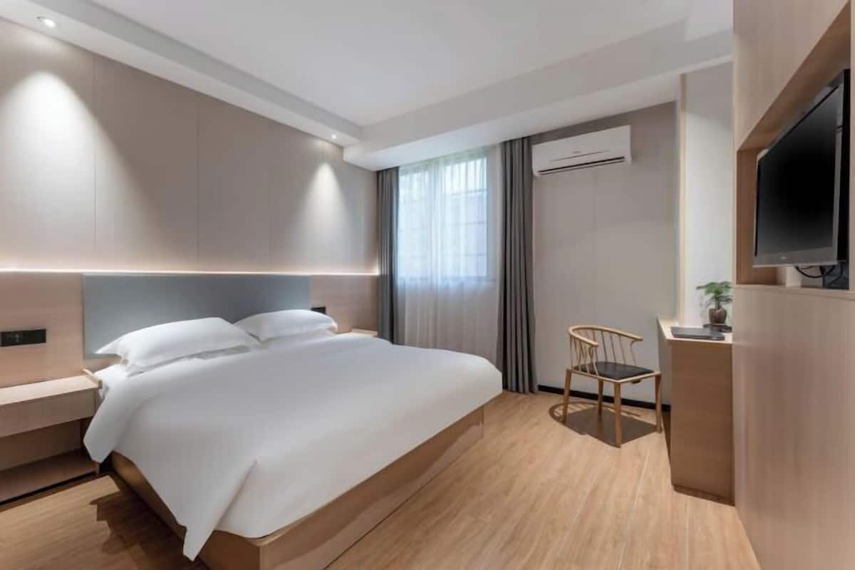 A modern hotel room with a large bed, a desk, and a TV.