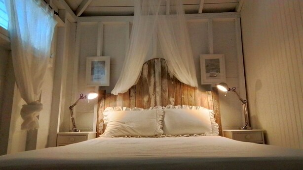 A bed with white bedding, two bedside lamps, and a wooden headboard.