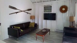 A living room with a dark brown sofa, a wooden coffee table, a TV mounted on the wall, and a large decorative clock.
