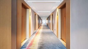 A long, narrow hotel corridor with wooden walls and a colorful carpet. - Thank You Intercity Hotel (Junan Leshang Building) (Junan County)