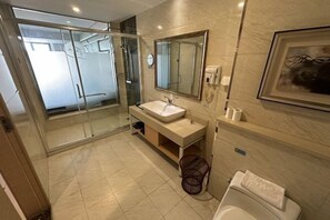 Une salle de bain moderne avec une douche à parois de verre, un lavabo avec un miroir et des toilettes.