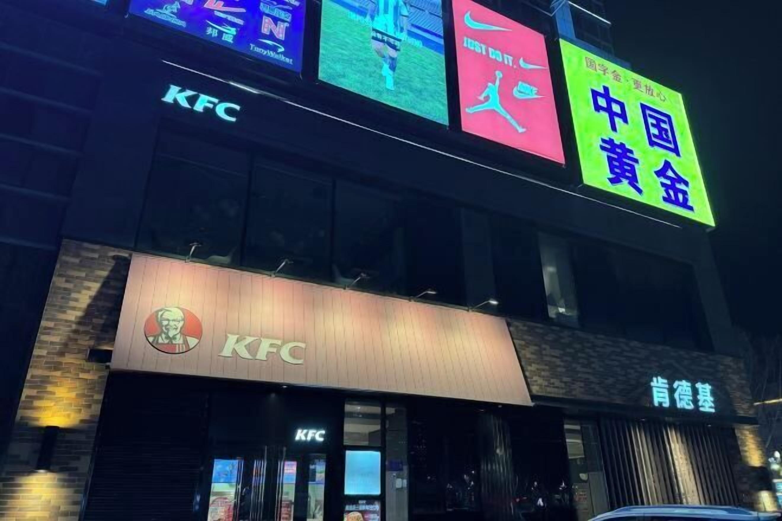 A KFC restaurant with neon signs in multiple languages and a visible entrance.