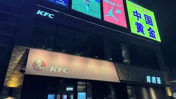 A KFC restaurant with neon signs in multiple languages and a visible entrance.