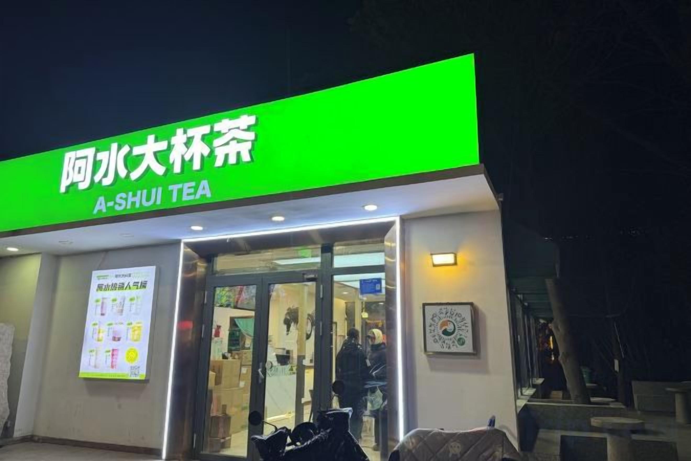 Una tienda de té con un letrero verde y entrada de vidrio.
