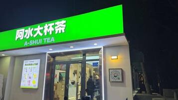 Una tienda de té con un letrero verde y entrada de vidrio.