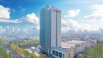 A tall hotel with a modern design, surrounded by a cityscape and greenery.