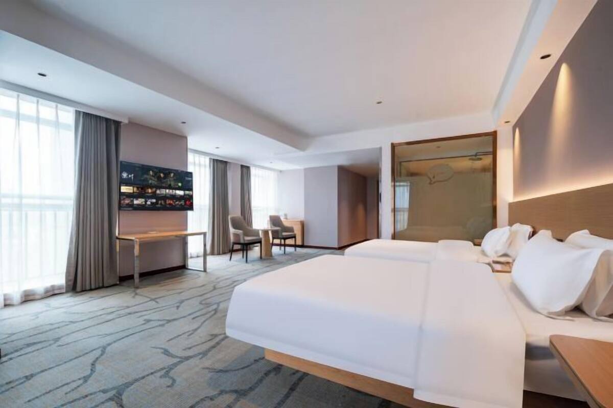 A hotel room with a large bed, a desk, a chair, and a television.