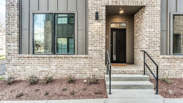 A modern building with a brick facade, large windows, and a black door. - Johnny Cash House • Walk to Bars & Dining (Nashville)