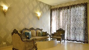 Una sala de estar con un conjunto de sofá antiguo, una mesa de centro y cortinas estampadas.