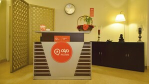 Una recepción con un reloj, un cartel que indica los horarios de entrada y salida, y una planta decorativa.