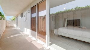 Un balcon avec un lit, une porte-fenêtre coulissante et une vue sur un jardin.