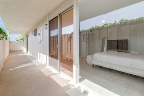 Un balcón con una cama, una puerta corrediza de vidrio y vistas a un jardín.