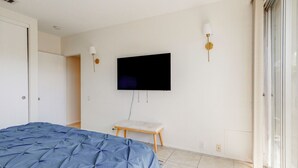 Une chambre à coucher avec un lit, un téléviseur fixé au mur et une petite table.