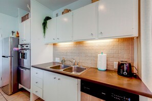 A kitchen with white cabinets, stainless steel appliances, and a tiled backsplash.
