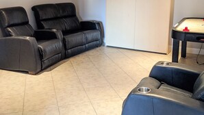 A room with a reclining sofa, a cabinet, and a foosball table. - Chalet Au petit Edouard (Mount Edouard) (L'Anse-Saint-Jean)