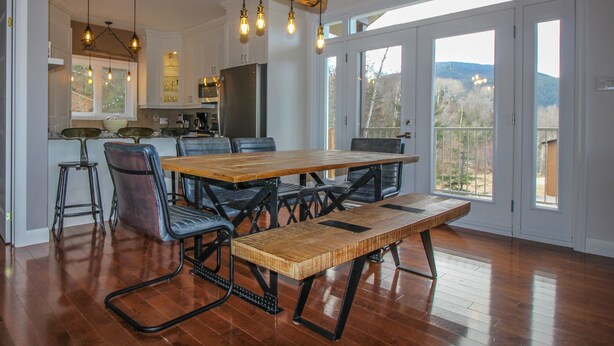 A spacious kitchen with a large wooden table and chairs, a refrigerator, and hanging light fixtures. - Chalet Au petit Edouard (Mount Edouard) (L'Anse-Saint-Jean)