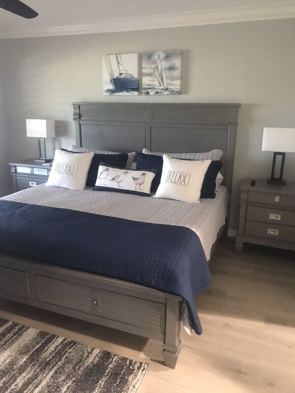 A bedroom with a bed, nightstands, a headboard, a wall-mounted painting, and a rug. - Spectacular water and golf course views (The Villages)