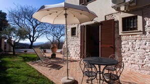 Een terras met een tafel, stoelen, een grote parasol en een stenen muur.